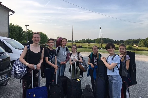 Sieben junge Musikerinnen und Musiker mit ihren Koffern und Instrumenten